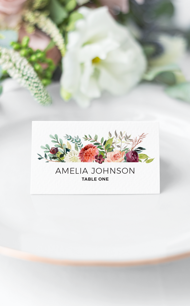 Burgundy floral seating card on white plate at Wedding reception